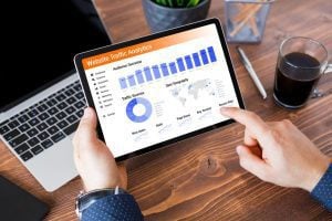 Man in office with data applications on laptop and iPad.